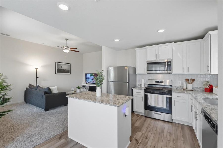 Kitchen with appliances with stainless steel finishes, tasteful backsplash, white cabinetry, open floor plan, and recessed lighting