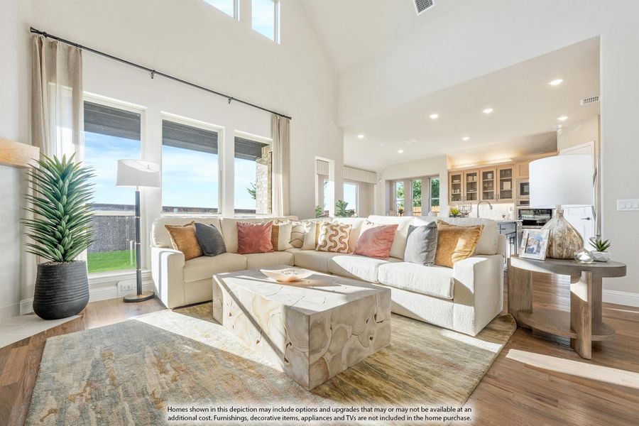 Open-concept living room with vaulted ceiling, sectional sofa, hardwood floors, and large windows overlooking backyard Open-concept living room with vaulted ceiling, sectional sofa, hardwood floors, and large windows overlooking backyard