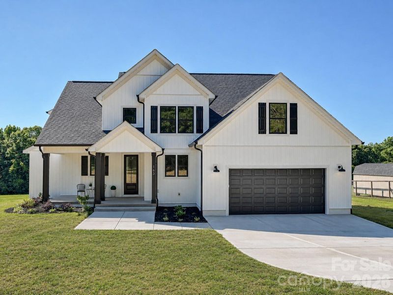Stunning, new construction, custom built home with inviting front porch, manicured landscaping, and striking curb appeal set against a bright, open homesite. (Concept grass)