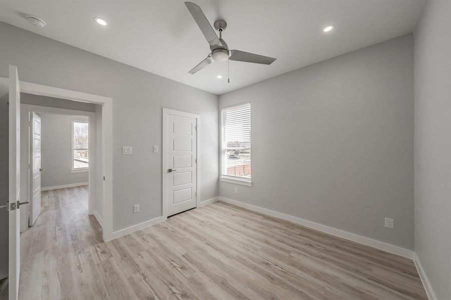 Unfurnished bedroom with multiple windows, ceiling fan, and light wood-type flooring