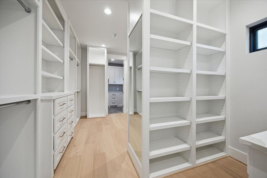 This spacious walk-in closet features ample shelving and drawer storage and a modern, well-lit design, perfect for organizing clothing and accessories.