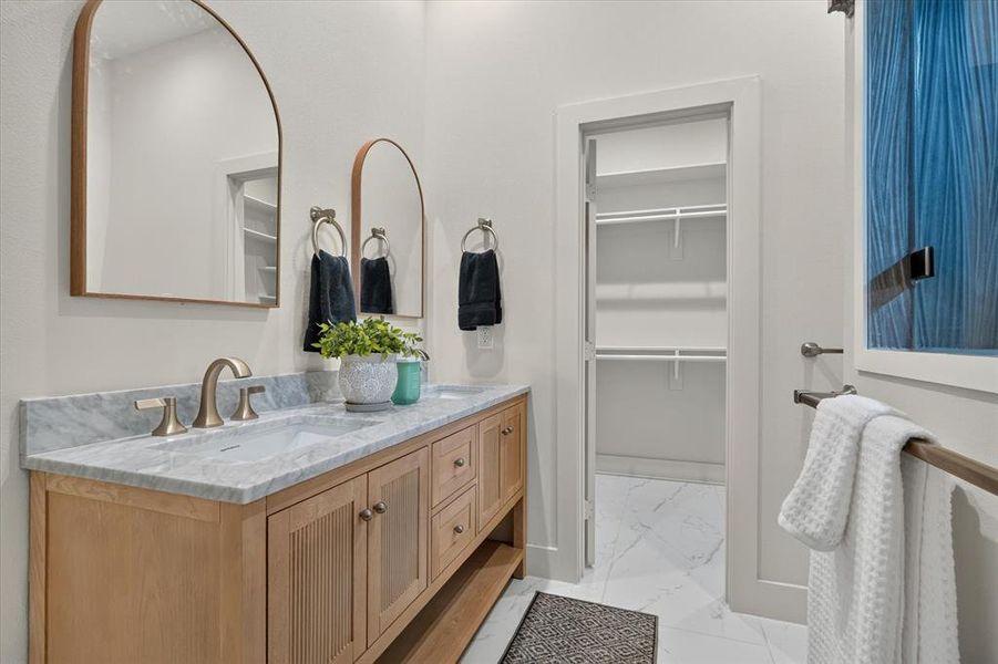 Dual vanity with integrated sinks, light-toned wood cabinetry, and a stone countertop