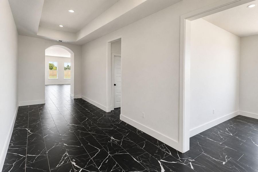 Black tile flooring and an arched doorway create a striking entryway.
