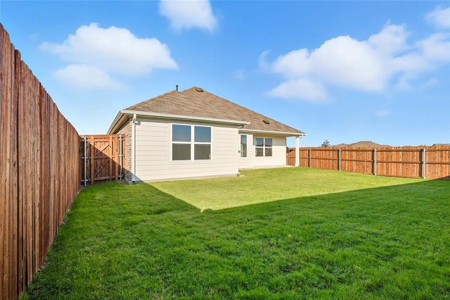 Back of house with a fenced backyard, a gate, and a shingled roof Back of house with a fenced backyard, a gate, and a shingled roof