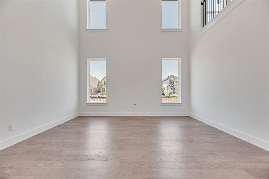 Unfurnished living room with a high ceiling and light wood-style flooring Unfurnished living room with a high ceiling and light wood-style flooring