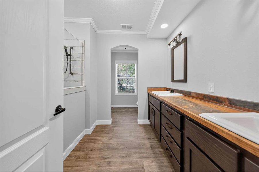 Full bathroom featuring ornamental molding, double vanity, light wood finished floors, and recessed lighting Full bathroom featuring ornamental molding, double vanity, light wood finished floors, and recessed lighting