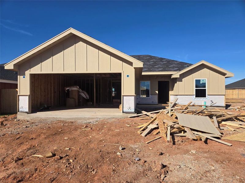 Property in mid-construction featuring a patio area, roof with shingles, and board and batten siding