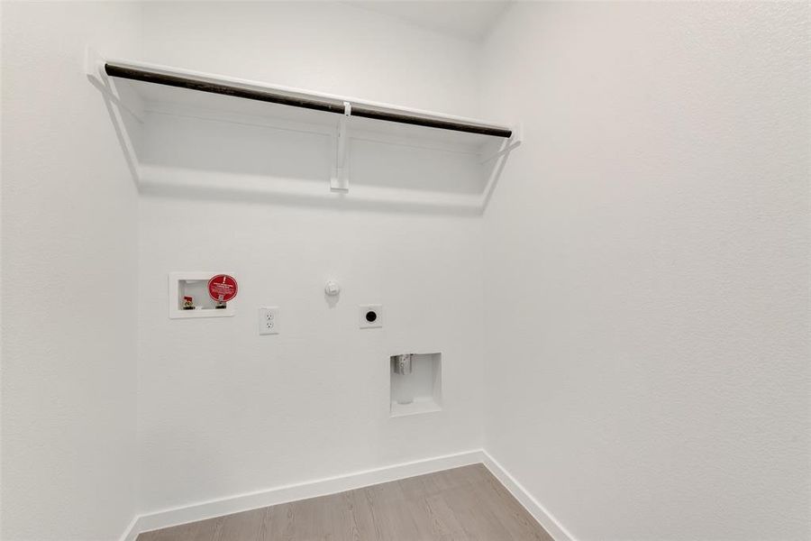 Washroom with gas dryer hookup, light wood finished floors, hookup for a washing machine, and electric dryer hookup Washroom with gas dryer hookup, light wood finished floors, hookup for a washing machine, and electric dryer hookup