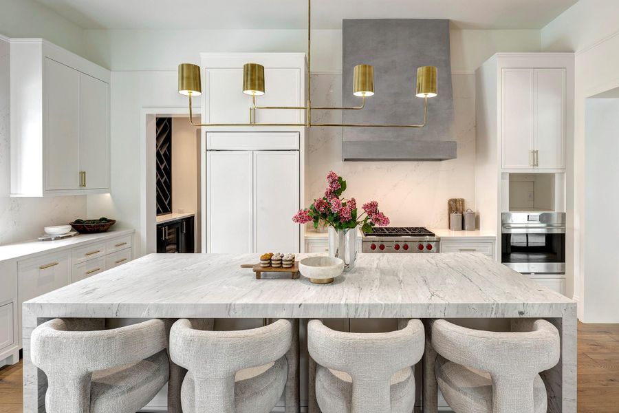 Light-filled and beautifully appointed, the dreamy kitchen is truly the heart of the home, centered around a honed Carrara marble waterfall island with bar stool seating.