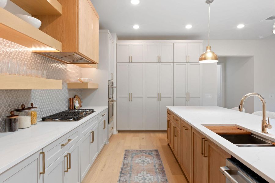 Kitchen with pendant lighting, light wood-style flooring, open shelves, a sink, and stainless steel appliances