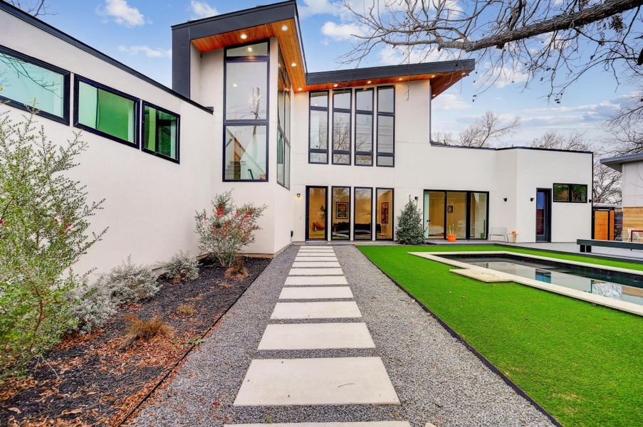 Back of property featuring stucco siding, an outdoor pool, and a yard