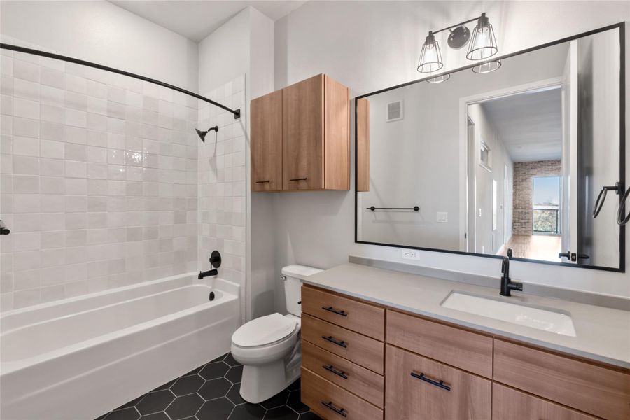 Bathroom with toilet, vanity,  shower combination, and tile patterned flooring