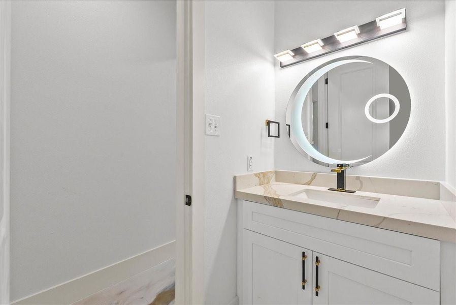 Modern powder bath with designer vanity and illuminated mirror.