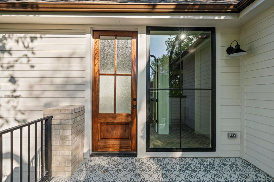 A welcoming entry features an elegant wood door with patterned glass and stylish tiled flooring.