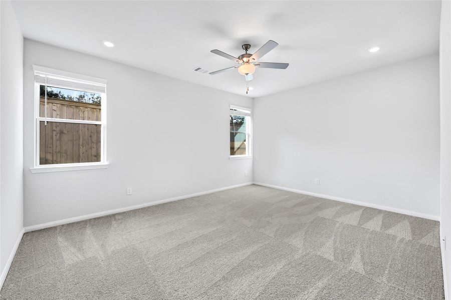This primary bedroom is bright and spacious with plush new carpet, two windows for natural light, and a ceiling fan with recessed lighting.Please note: The image is not the actual home; it is a home with the same floor plan in the neighborhood.