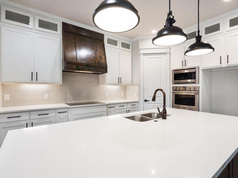 Kitchen featuring stainless steel appliances, white cabinetry, a kitchen island with sink, and sink