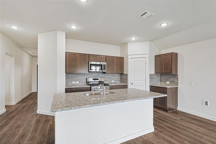 Kitchen featuring sink, appliances with stainless steel finishes, a kitchen island with sink, and dark hardwood / wood-style floors