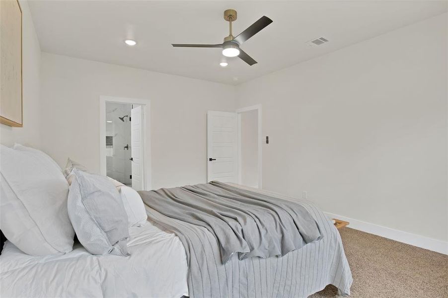 Bedroom with connected bathroom, ceiling fan, and carpet floors