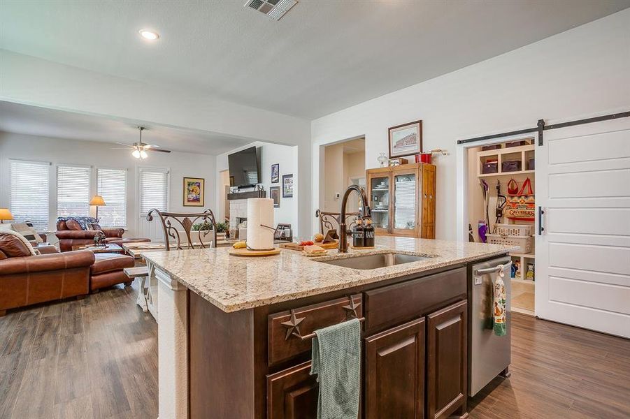 Kitchen with dark brown cabinets, a barn door, light stone counters, dark wood finished floors, and recessed lighting Kitchen with dark brown cabinets, a barn door, light stone counters, dark wood finished floors, and recessed lighting