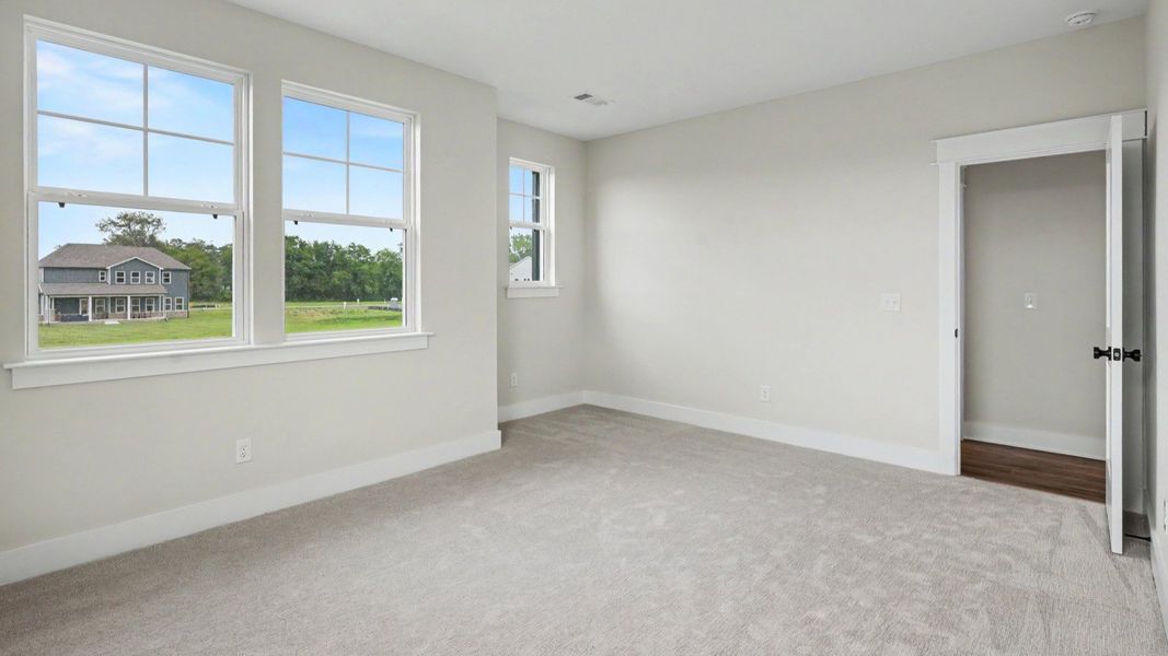 Secondary bedroom with windows and carpet