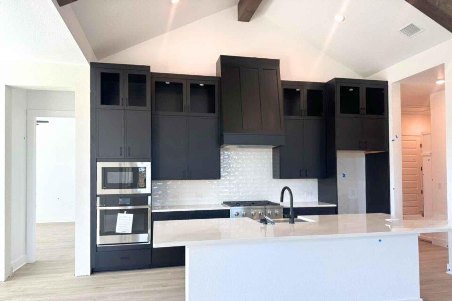 Kitchen featuring appliances with stainless steel finishes, premium range hood, light wood-type flooring, tasteful backsplash, and a kitchen island with sink Kitchen featuring appliances with stainless steel finishes, premium range hood, light wood-type flooring, tasteful backsplash, and a kitchen island with sink