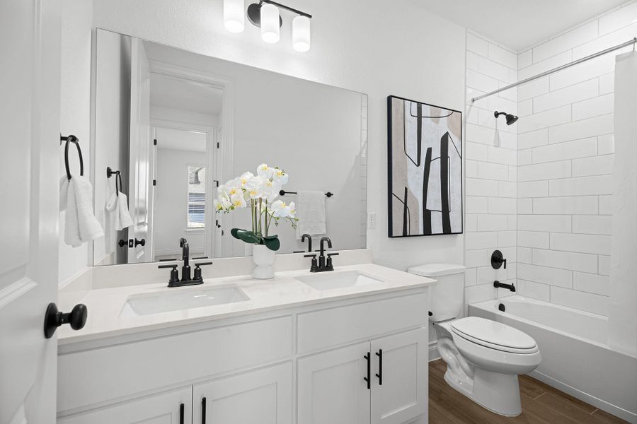Full bath with bathtub / shower combination, dark wood-style flooring, and double vanity