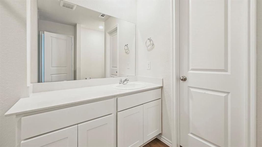 White vanity with an integrated sink, polished chrome faucet, and expansive wall-mounted mirror