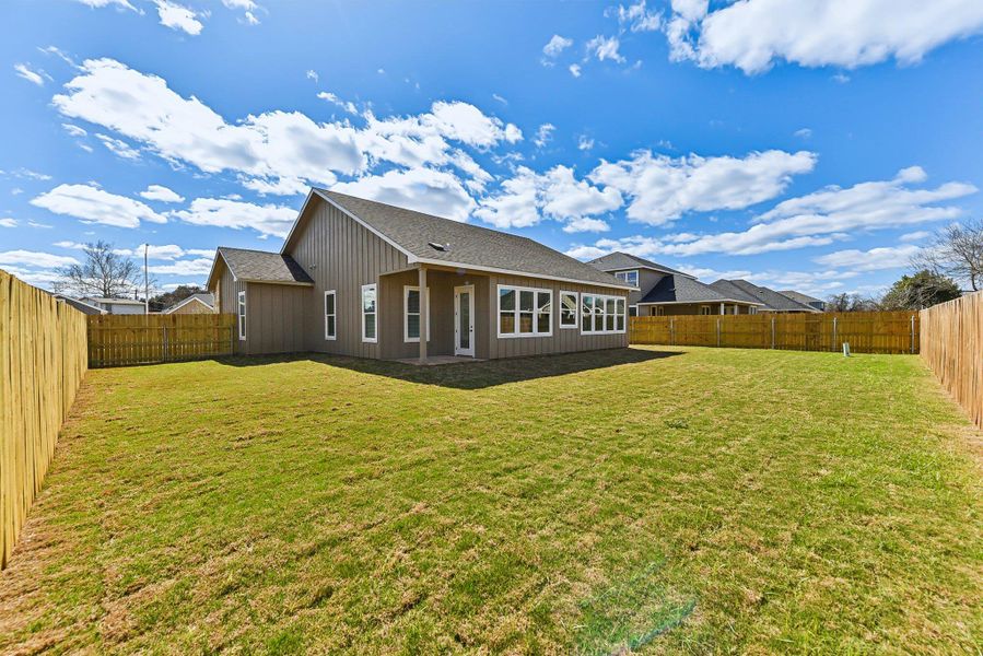 Rear view of property with a fenced backyard, a yard, and roof with shingles Rear view of property with a fenced backyard, a yard, and roof with shingles