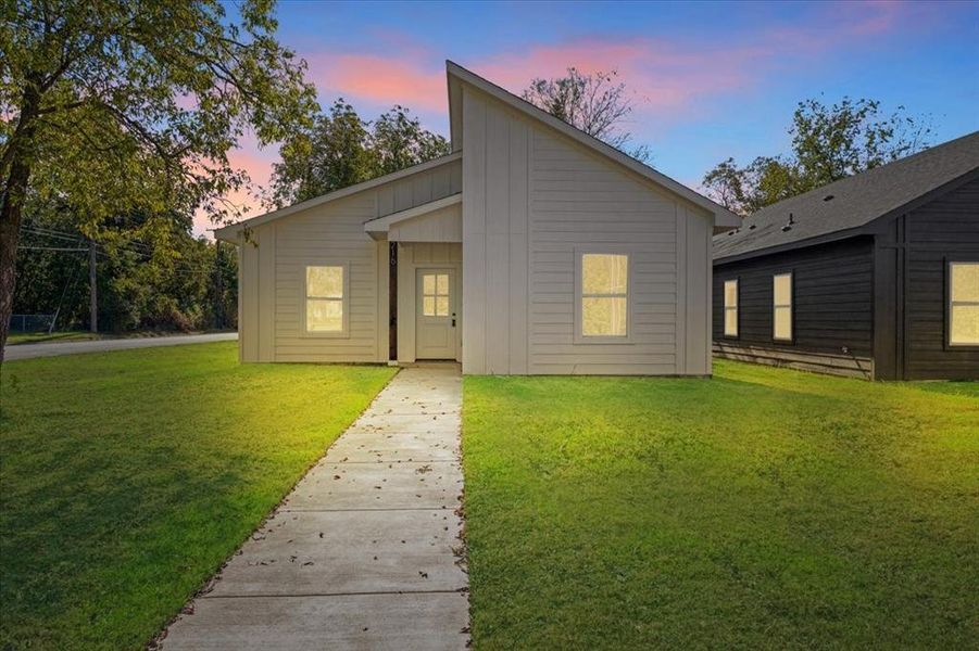 Back house at dusk with a lawn