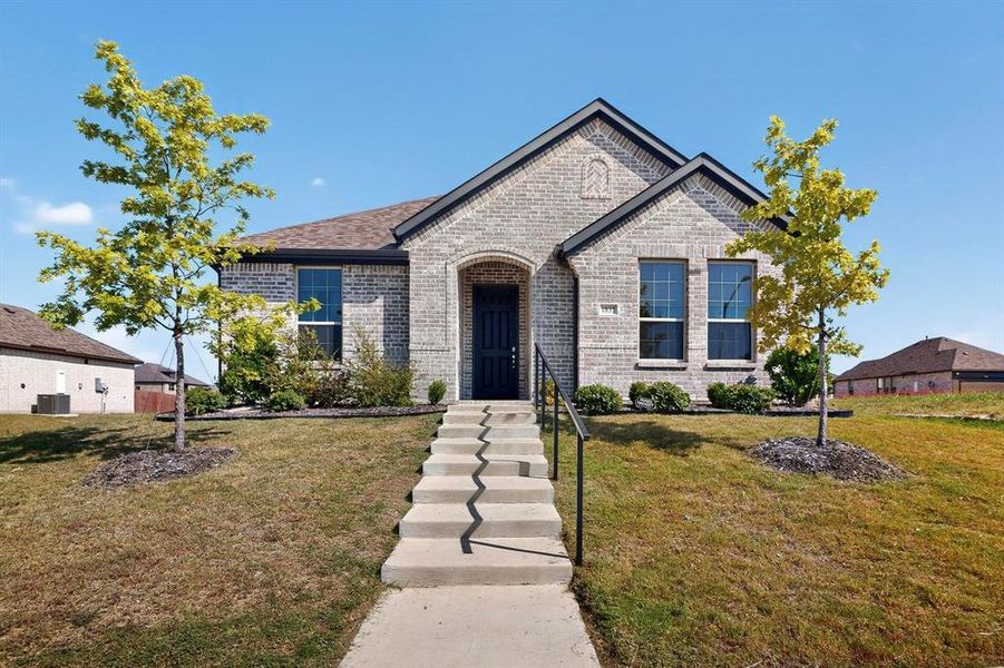 French country home featuring brick siding and a front yard French country home featuring brick siding and a front yard