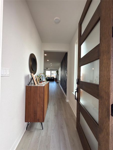 Entryway featuring a contemporary wooden door with frosted glass panels, light wood-finish flooring, and recessed ceiling lighting