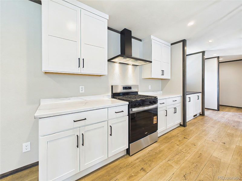 Kitchen – Updated kitchen with sleek countertops, gas range, and vent hood, complemented by clean-lined cabinetry and contemporary finishes.