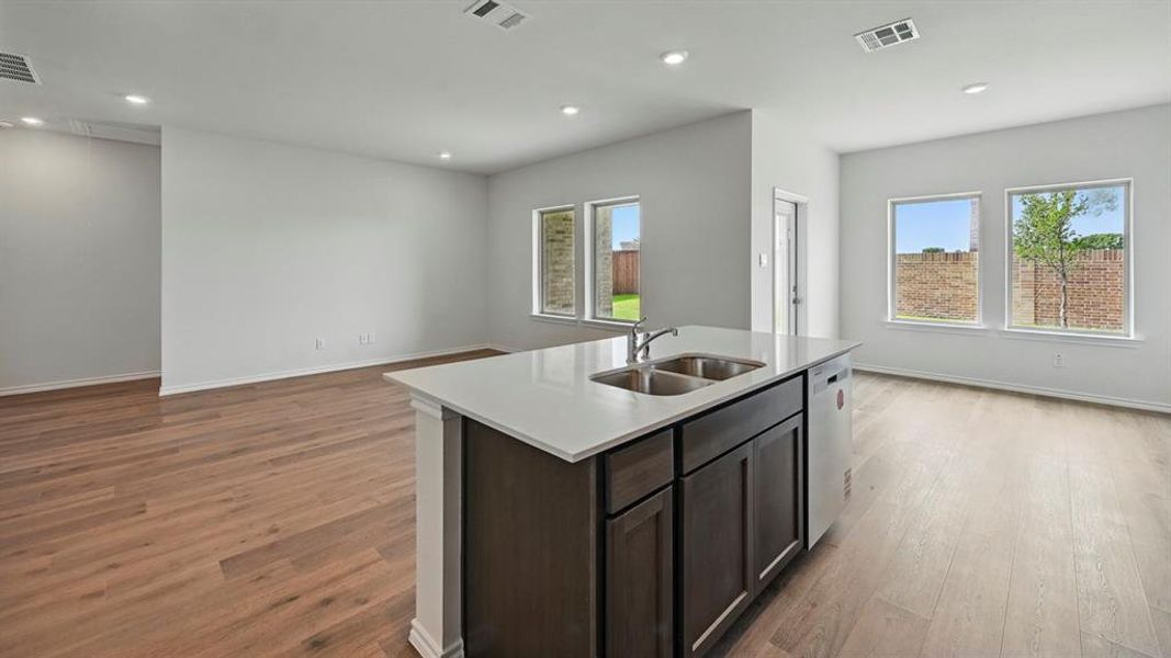 Kitchen with an island with sink, dark brown cabinets, recessed lighting, light wood-type flooring, and open floor plan