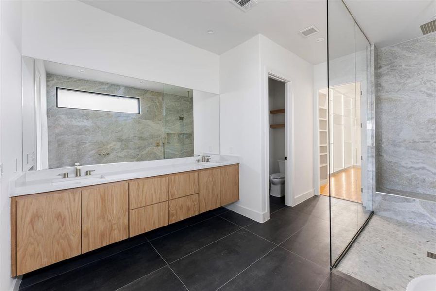 Full bathroom with double vanity, a walk in shower, dark tile patterned floors, a walk in closet, and recessed lighting Full bathroom with double vanity, a walk in shower, dark tile patterned floors, a walk in closet, and recessed lighting