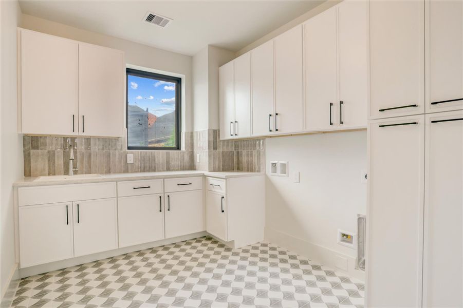 The spacious utility room also sits on the second floor and offers plenty of cabinet storage, counter space, utility sink, and natural light.