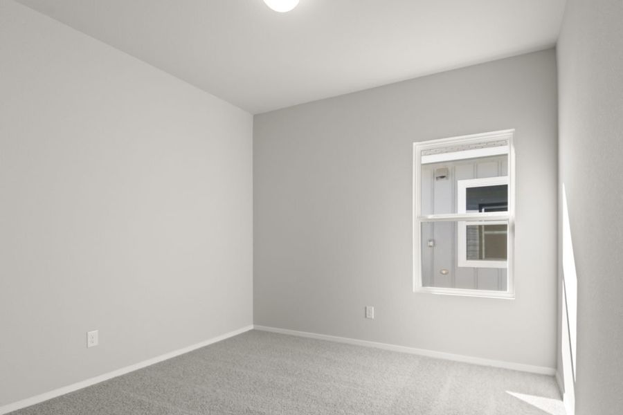 Image of a bedroom with light grey walls, tan carpeting, white trim and a window