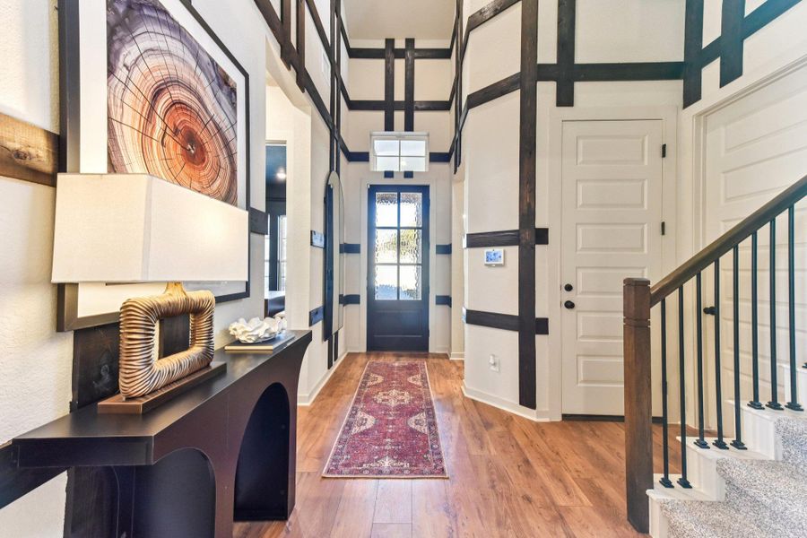 A striking two-story entryway welcomes guests with a decorative front door and warm hardwood flooring. A striking two-story entryway welcomes guests with a decorative front door and warm hardwood flooring.
