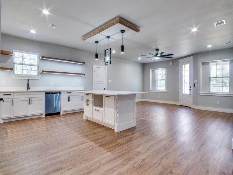 Kitchen with dishwasher, white cabinets, plenty of natural light, and hanging light fixtures