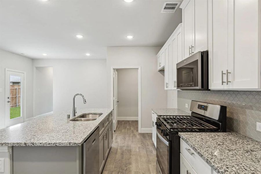 Kitchen featuring white cabinets, sink, and appliances with stainless steel finishes