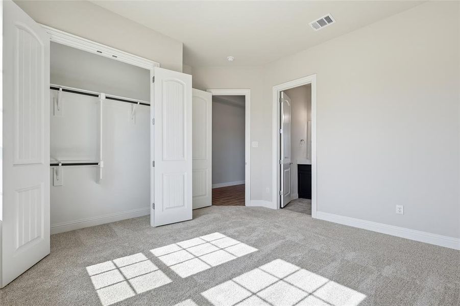 Unfurnished bedroom featuring light colored carpet, a closet, and ensuite bath Unfurnished bedroom featuring light colored carpet, a closet, and ensuite bath
