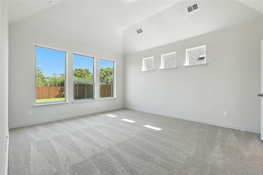 Carpeted empty room featuring vaulted ceiling and baseboards