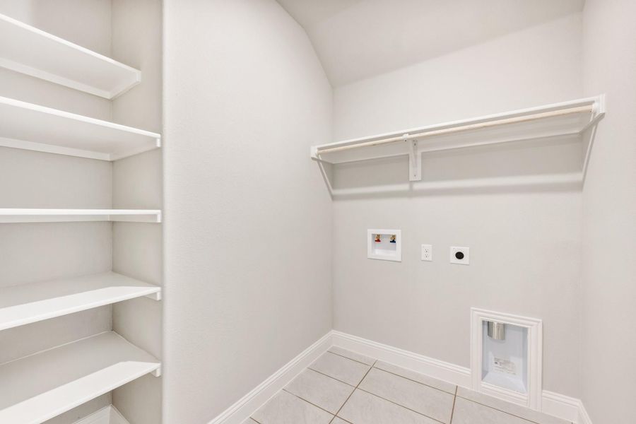 Laundry room with white shelving, hanging rod, washer hookups, and tile floor Laundry room with white shelving, hanging rod, washer hookups, and tile floor