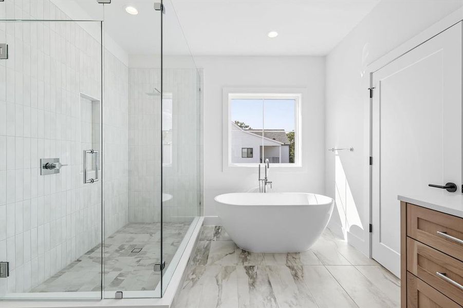 Full bath featuring a shower stall, a freestanding tub, vanity, recessed lighting, and light marble finish flooring Full bath featuring a shower stall, a freestanding tub, vanity, recessed lighting, and light marble finish flooring