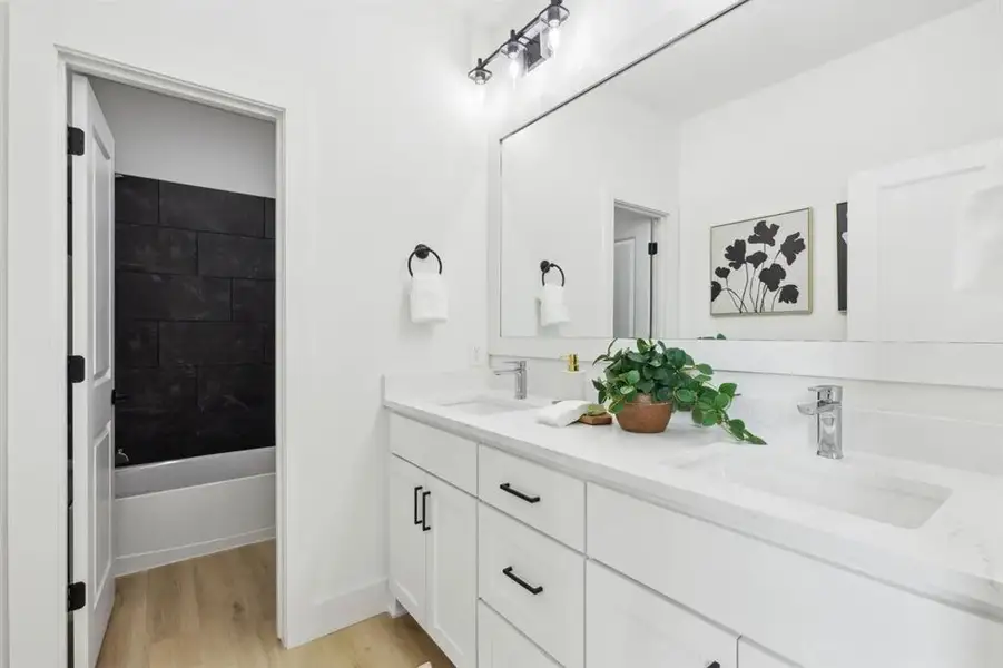 Full bathroom featuring double vanity, light wood-style flooring, and bathing tub / shower combination