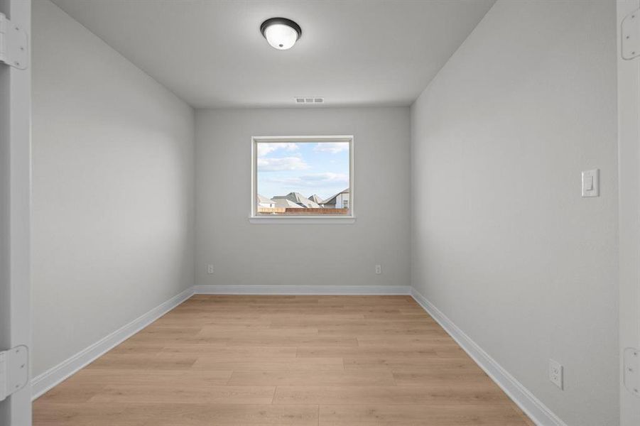 Neutral-toned room with wood-finish flooring, white baseboards, and a single window Neutral-toned room with wood-finish flooring, white baseboards, and a single window