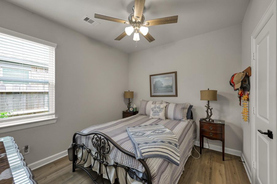 Comfortable secondary bedroom featuring luxury vinyl plank flooring, ceiling fan, generous closet space, and a large window that fills the room with natural light. Comfortable secondary bedroom featuring luxury vinyl plank flooring, ceiling fan, generous closet space, and a large window that fills the room with natural light.