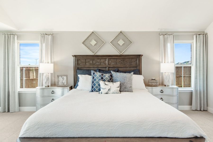 Master bedroom with king bed, dark wood headboard, two windows with white curtains, and matching nightstands