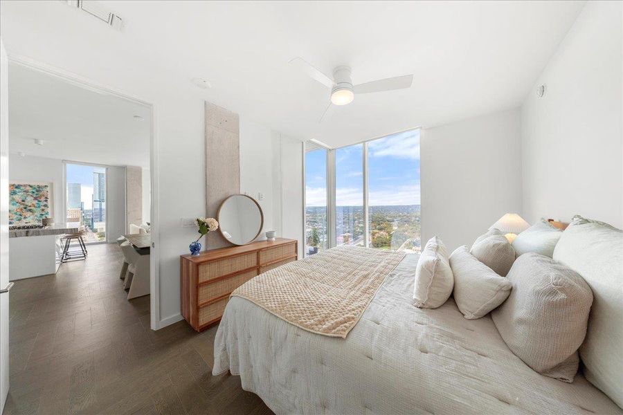 Serene primary bedroom framed by floor-to-ceiling glass with sweeping Hill Country views, offering a calming retreat just steps from the open-concept living space.