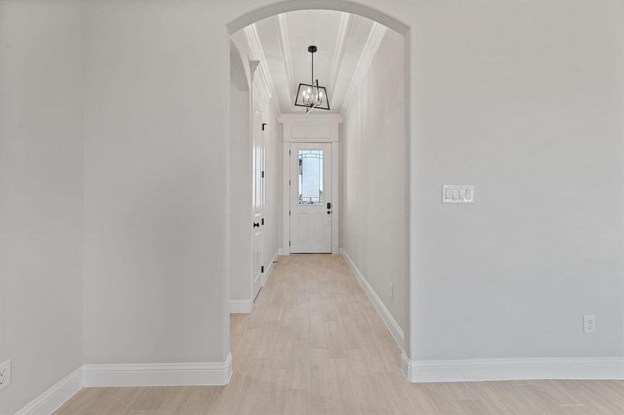 Doorway to outside featuring arched walkways, wood finished floors, and a chandelier