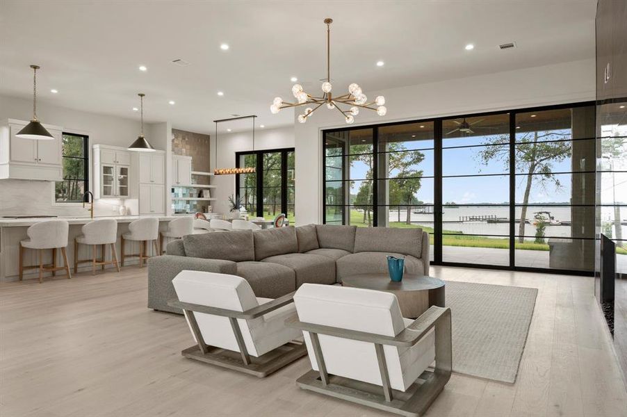 Living area with a chandelier, light wood-type flooring, a water view, recessed lighting, and plenty of natural light Living area with a chandelier, light wood-type flooring, a water view, recessed lighting, and plenty of natural light